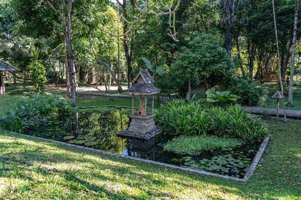 A garden pond with a spirit house made in teak wood Rai Mae Fah Luang, Chiang Rai, Thailand